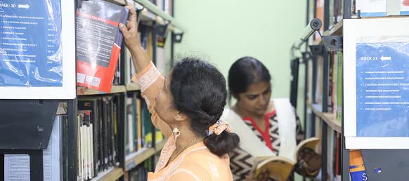 Library staff browsing books on the shelves