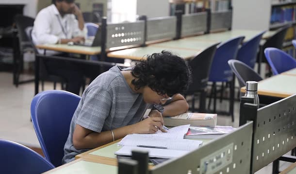 Student taking notes at a library reading table